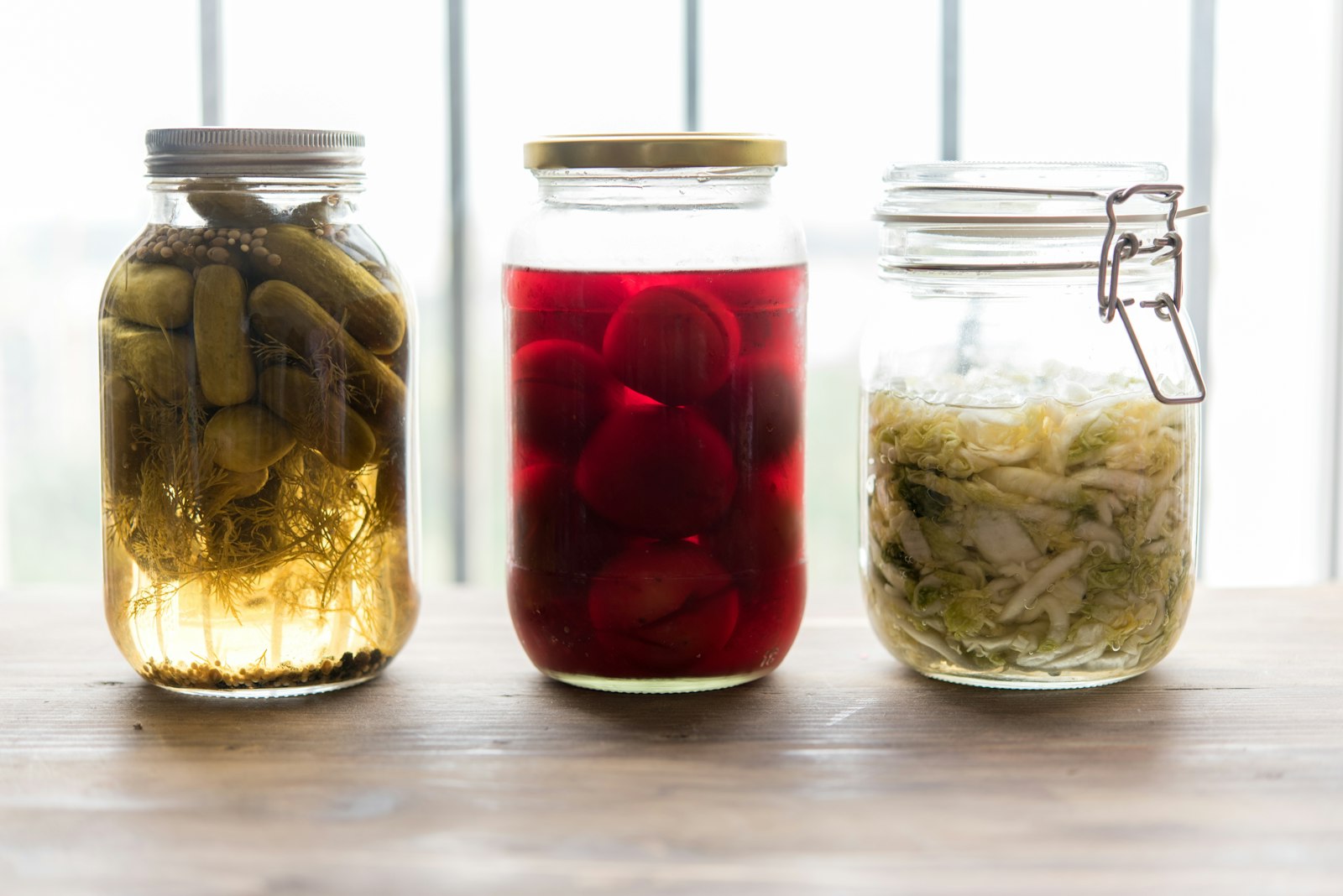 Trois bocaux remplis de différents aliments fermentés